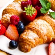Fresh tasty croissants with berries on wooden background
